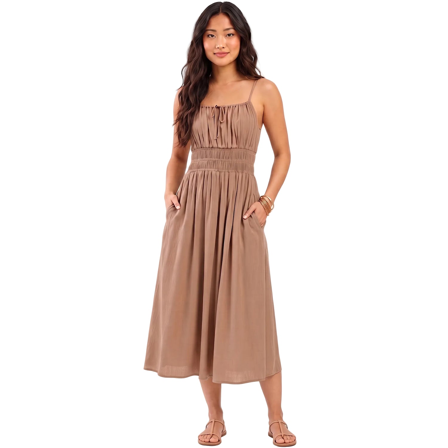 A woman modeling a sleeveless midi dress in a warm taupe-brown color, featuring a gathered smocked bodice, thin shoulder straps, and side pockets. The brand name 'AURA' is printed in black text on the left side of the image, set against a solid pale beige background.