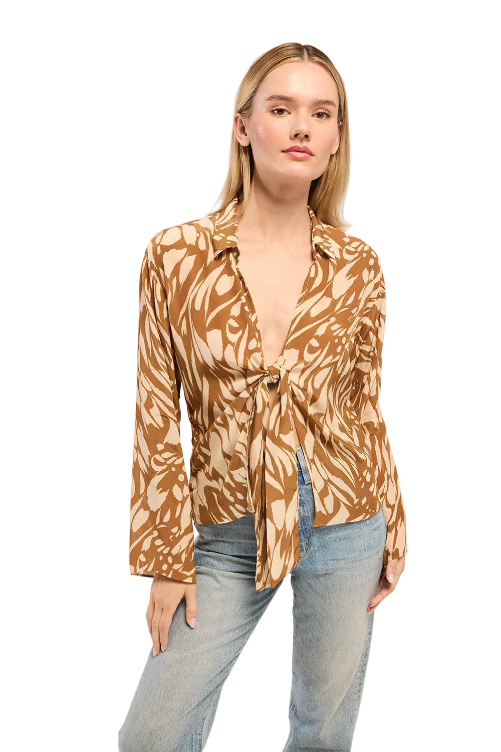 Woman wearing a patterned blouse and jeans on a plain background