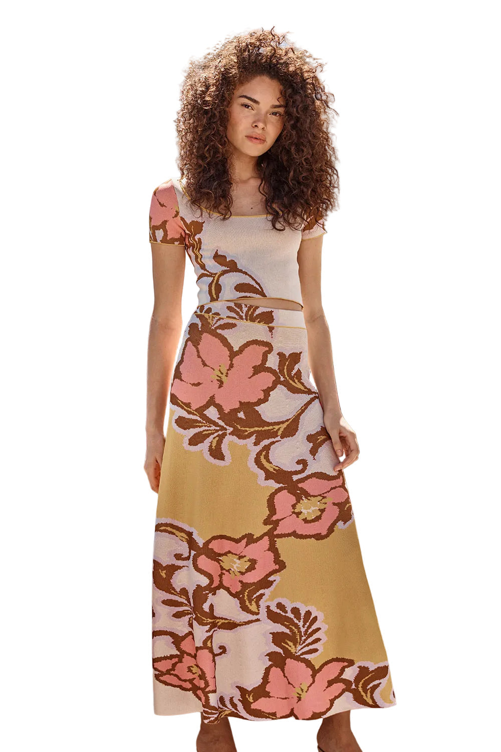 Woman wearing a floral dress standing outdoors with greenery in the background